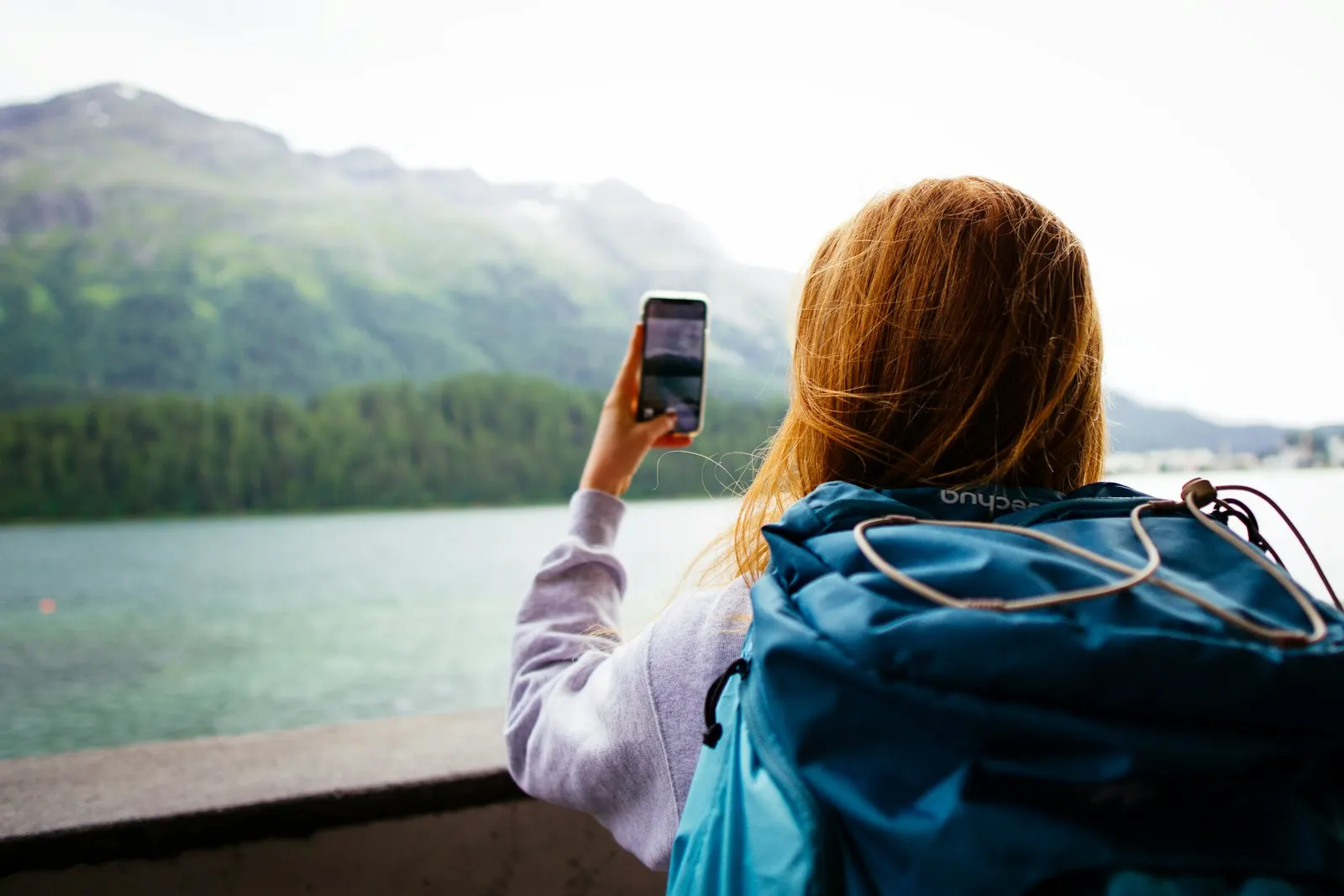 Hiker with a phone at a mountain lake